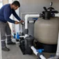 Técnico ajustando válvulas de filtro bomba manômetro e tubulações em casa de máquinas de piscina