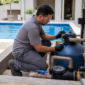 Técnico verificando manômetro em filtro de areia bomba e tubulações de casa de máquinas de piscina residencial