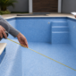 Técnico medindo o interior de uma piscina revestida de vinil antes da troca