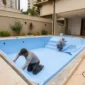 Equipe técnica ajustando o revestimento de vinil em piscina residencial durante a obra no Setor Sudoeste, Goiânia