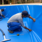 Técnicos ajustando o novo vinil azul durante a troca de revestimento de uma piscina