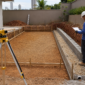 Profissional avaliando drenagem e estrutura em terreno inclinado para piscina