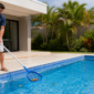 Pessoa removendo folhas e conferindo a piscina antes de uma viagem