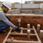Técnico usando manômetro para testar a estanqueidade das tubulações de sucção e retorno de uma piscina em construção em Goiânia.