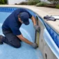 Técnico medindo parede de piscina com vinil antigo parcialmente removido para troca segura