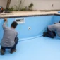 Técnicos medindo revestimento de vinil azul em piscina residencial durante reforma