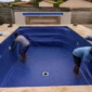 Técnicos instalando bolsão de vinil azul em piscina residencial vazia no Setor dos Afonsos