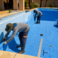 Equipe instalando bolsão de vinil azul em piscina residencial vazia