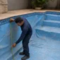 Técnico medindo piscina vazia com vinil azul desgastado antes da troca do revestimento