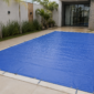 Capa de piscina azul instalada e fixada ao redor de uma piscina residencial em Goiânia, com perímetro livre.