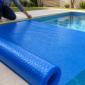 Profissional medindo e instalando capa térmica azul de bolhas sobre piscina em Colinas do Sul