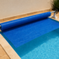 Capa térmica azul para piscina parcialmente enrolada em rolo de armazenamento em Vila Propício