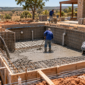 Equipe técnica trabalhando na estrutura de uma piscina de alvenaria em obra, com formas, armação e concreto