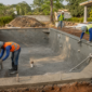 Piscina de concreto em construção com trabalhadores usando EPI e conferindo tubulações em Araguapaz