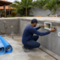 Piscina residencial em construção em Itarumã com técnico medindo a estrutura e tubulações hidráulicas aparentes
