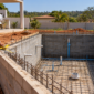 Piscina de alvenaria em construção com blocos armadura hidráulica embutida e técnico medindo o nível da borda