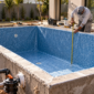 Piscina residencial em construção com técnico medindo a borda, revestimento de vinil e tubulações hidráulicas no Setor Urias Magalhães, Goiânia