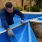 Técnico medindo revestimento de vinil azul durante troca de vinil de piscina em Inaciolândia