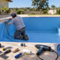 Profissional ajustando revestimento de vinil azul em piscina residencial durante a instalação