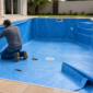Técnico medindo e ajustando o revestimento de vinil azul dentro de uma piscina em reforma