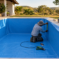 Profissional medindo e ajustando revestimento de vinil em piscina em Santo Antônio da Barra