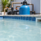 Água leitosa e turva na piscina com filtro de areia, bomba, manômetro e skimmer visíveis.
