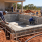 Equipe técnica construindo piscina de alvenaria com tubulação hidráulica e conferência de nível