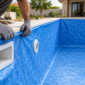 Instalador ajustando manta de vinil azul no acabamento de uma piscina em Vila Propício