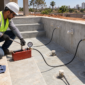 Técnico com manômetro realizando teste de pressão nas tubulações da piscina de alvenaria.