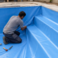 Técnico ajustando a manta de vinil azul nos degraus de uma piscina em reforma no Jardim das Acácias Norte